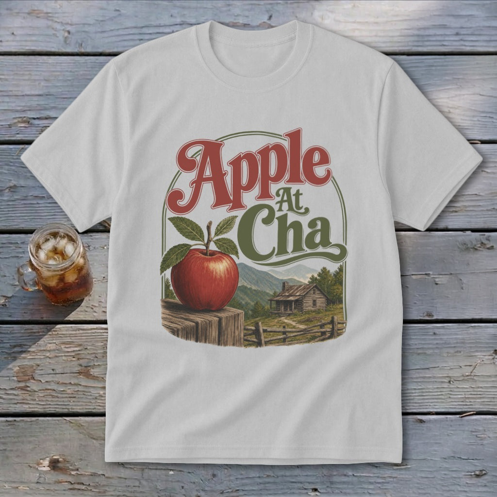 Light gray t-shirt featuring a retro graphic of an apple on a fence before a rustic cabin.