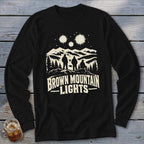 Black long-sleeve shirt with a graphic of mountains, figures, and stars, and text reading Brown Mountain Lights.