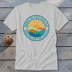 Light gray t-shirt with a vintage round graphic featuring mountains, a rising sun, and text reading BORN IN THE HOLLER RAISED ON THE RIDGE.