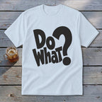 A white short-sleeve t-shirt with black text that reads "Do What?" lies on a weathered wooden surface next to a glass of iced tea.
