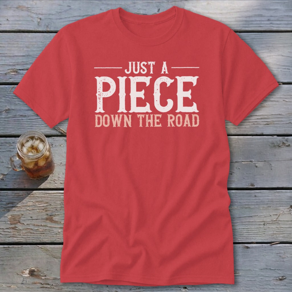 Red t-shirt with white distressed text reading "JUST A PIECE DOWN THE ROAD".