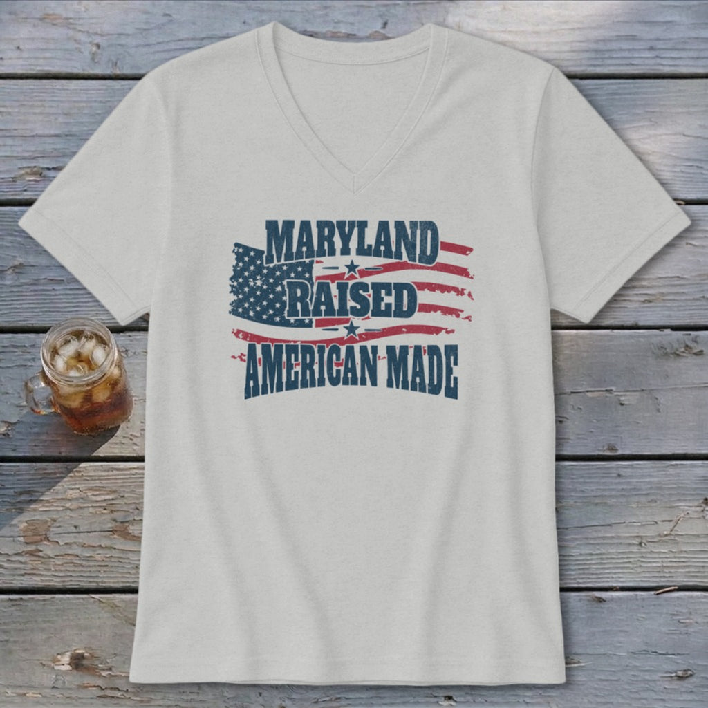 A light gray V-neck t-shirt with a distressed graphic of the American flag and the text Maryland Raised American Made.