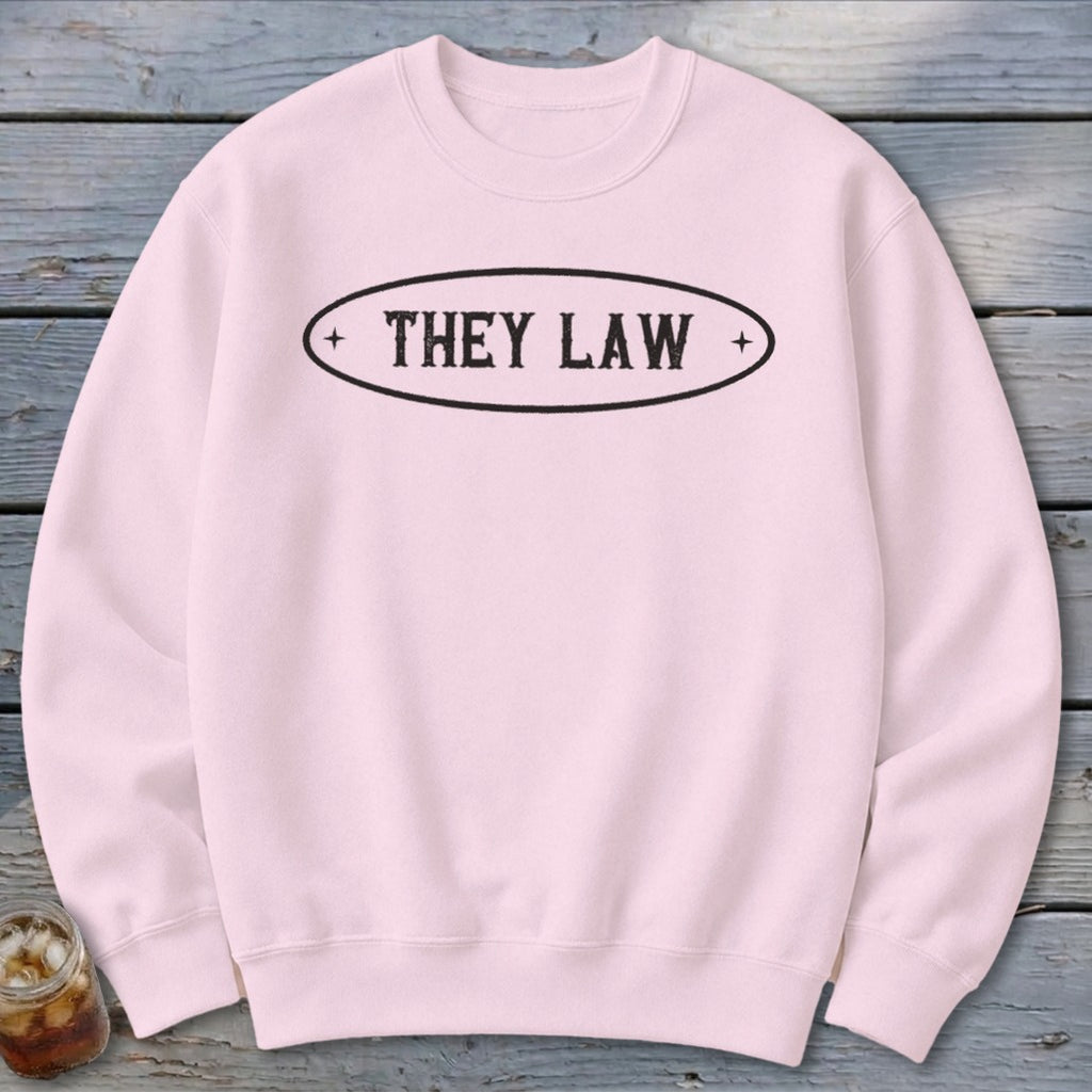 Light pink sweatshirt with black text "THEY LAW" inside an oval.