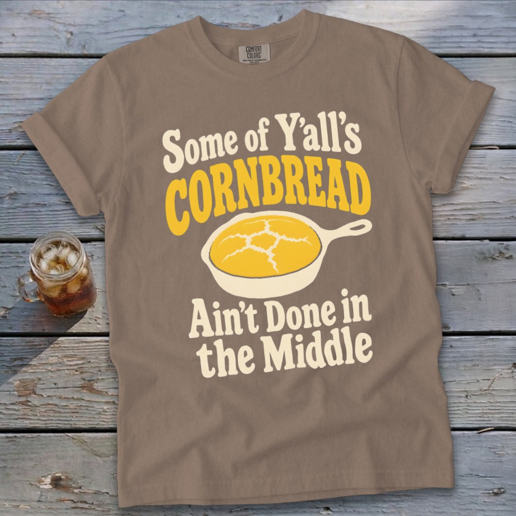 Brown t-shirt featuring the text "Some of Y'all's Cornbread Ain't Done in the Middle" and a cast-iron skillet graphic.