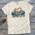 Cream t-shirt with heart framing a mountain sunrise and "Appalachia Strong" text.