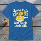 Blue t-shirt featuring a graphic of cornbread in a skillet and text reading Some of Yall's Cornbread Ain't Done in the Middle