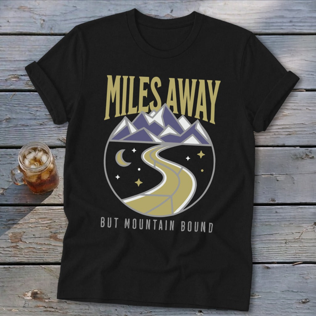 Black t-shirt with "MILES AWAY" above a circular mountain road design and "BUT MOUNTAIN BOUND" text.