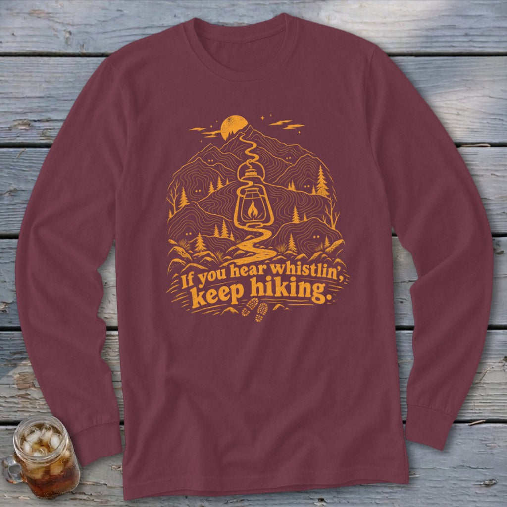 Maroon long-sleeve shirt with mountain, lantern, and "If you hear whistlin', keep hiking" text graphic.