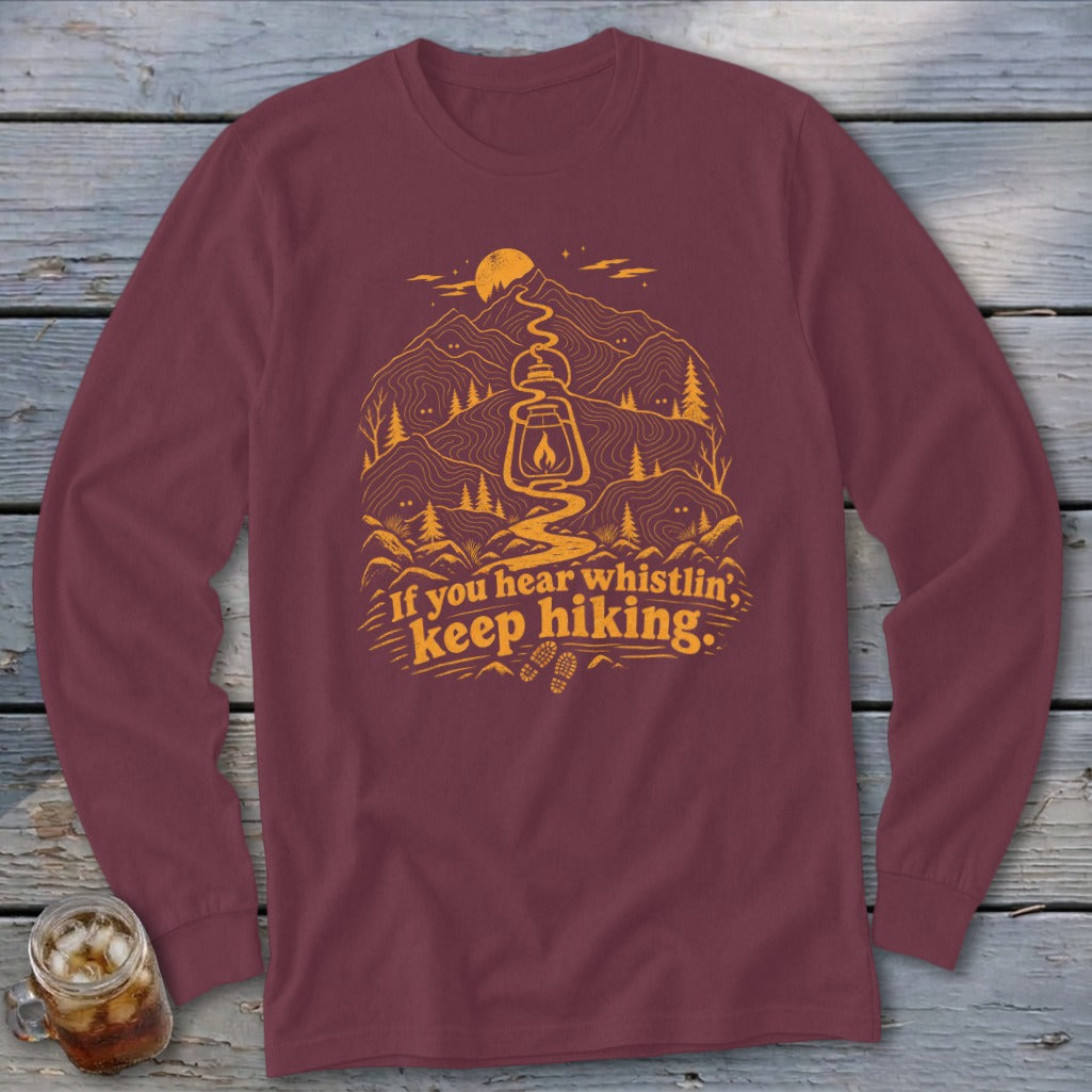 Maroon long-sleeve shirt with mountain, lantern, and "If you hear whistlin', keep hiking" text graphic.