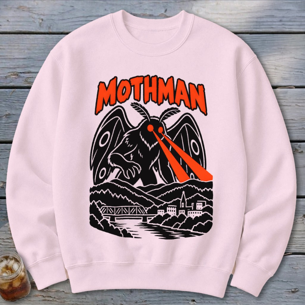 Pink sweatshirt featuring a black mothman with red eyes and a town below.
