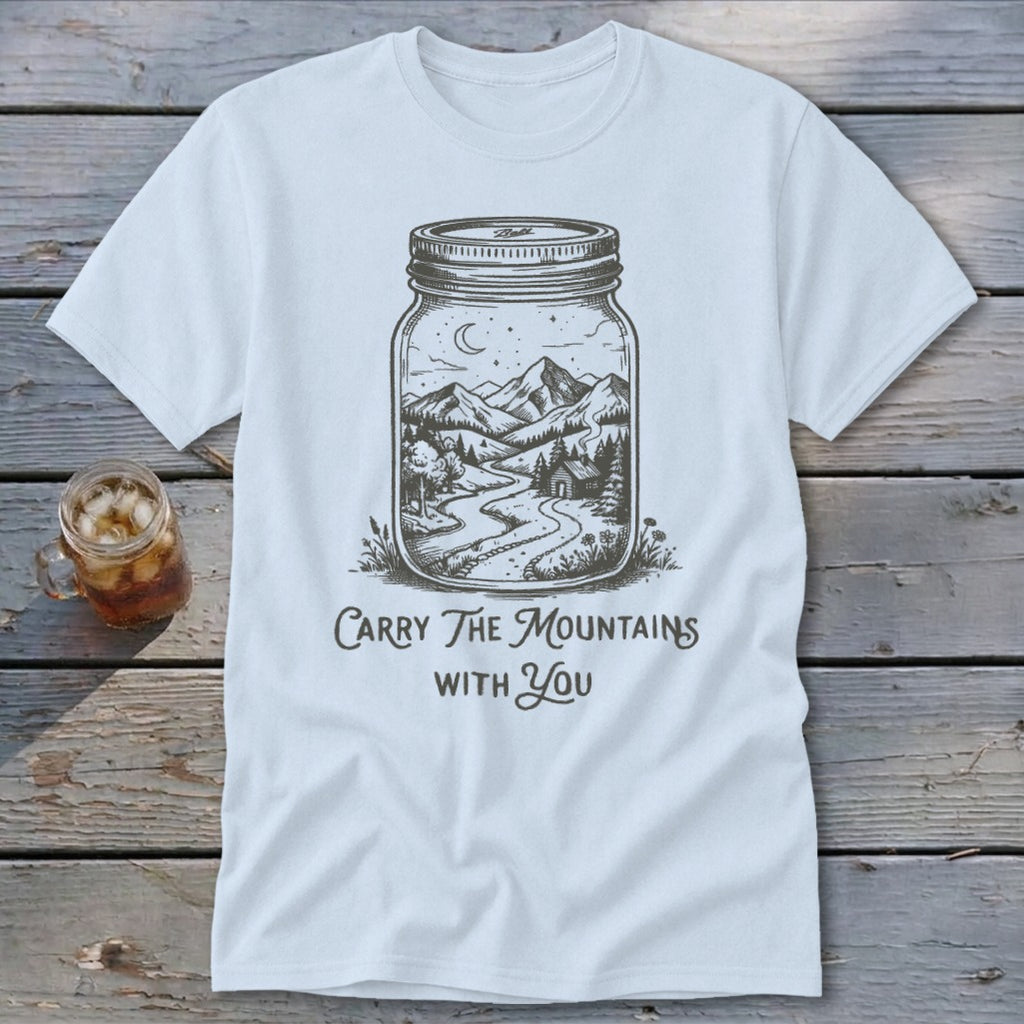 A white t-shirt featuring a mason jar illustration filled with a mountain landscape and text reading Carry The Mountains With You.
