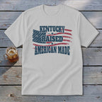 White t-shirt with American flag graphic and text "KENTUCKY RAISED AMERICAN MADE".