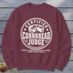 Maroon crewneck sweatshirt with a white emblem reading Certified Cornbread Judge and disqualification rules underneath.