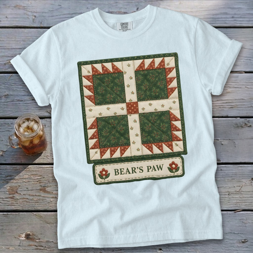 White t-shirt with a quilted "Bear's Paw" design featuring green, red, and cream fabrics.