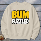 Beige crewneck sweatshirt featuring the text BUM FUZZLED in bold yellow and white letters.