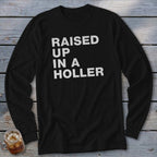 Black long-sleeved shirt with white text reading "RAISED UP IN A HOLLER".