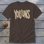 Brown t-shirt with "YOU'UNS" text in beige, next to a glass of iced tea.