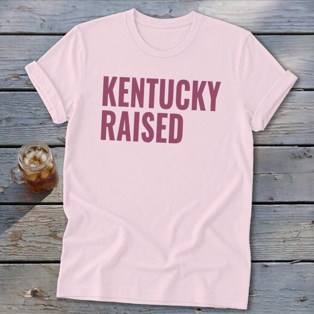 Pink t-shirt with "KENTUCKY RAISED" in maroon text and a drink on the side.