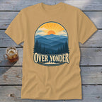 Tan t-shirt featuring a mountain sunset graphic with the text Over Yonder on a wooden background.