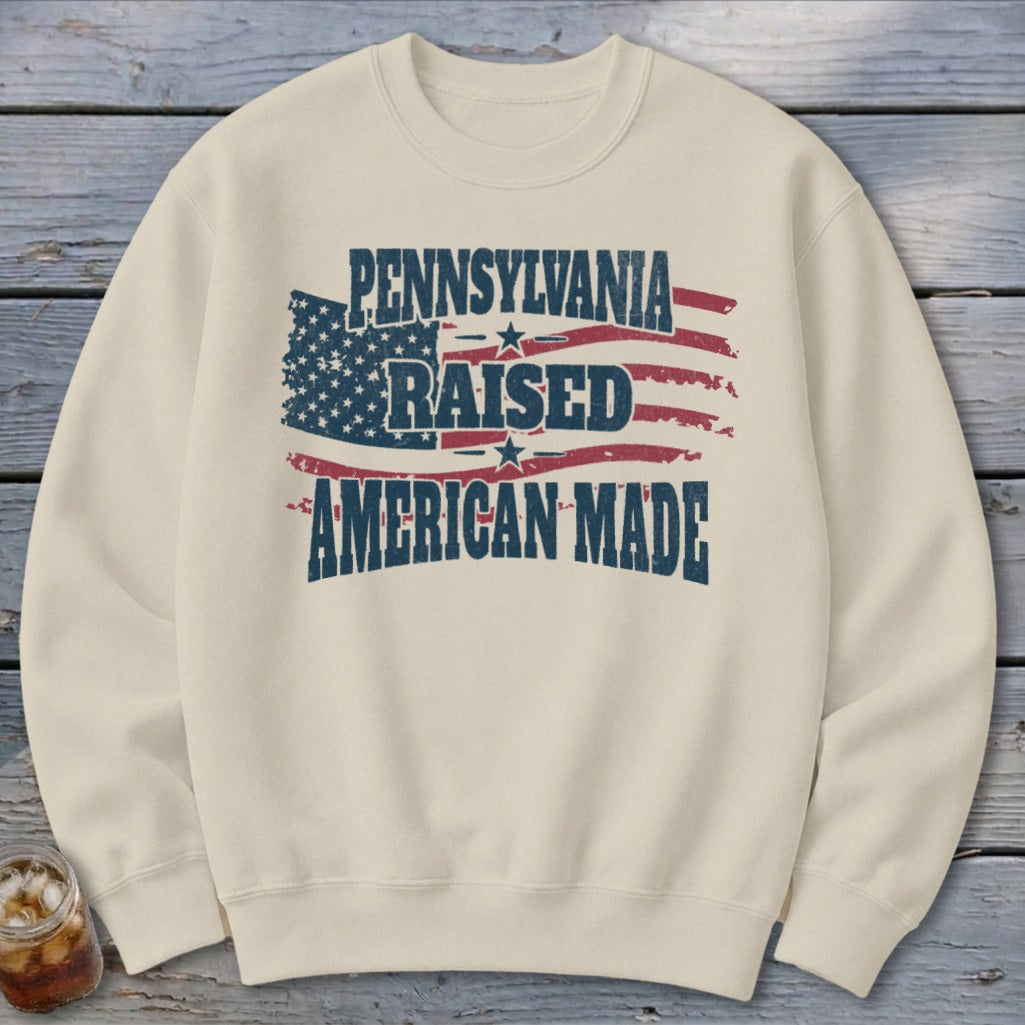 Beige crewneck sweatshirt featuring a distressed American flag design with the text Pennsylvania Raised American Made.