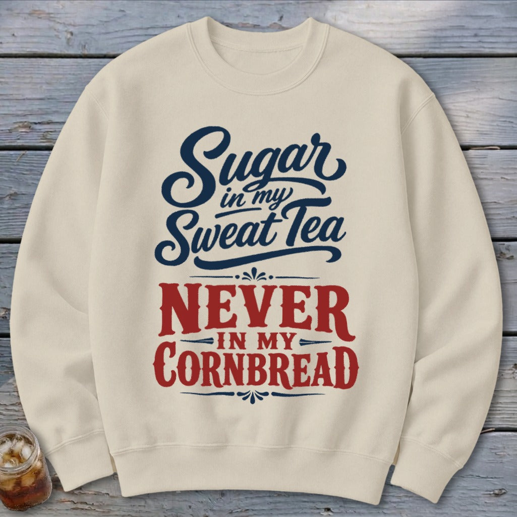 A cream crewneck sweatshirt printed with the blue and red text "Sugar in my sweet tea never in my cornbread."