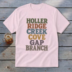 Light pink t-shirt featuring stacked multicolored text reading HOLLER RIDGE CREEK COVE GAP BRANCH.