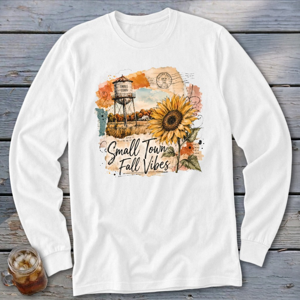White long sleeve shirt with a distressed graphic of a water tower, sunflower, and text "Small Town Fall Vibes".