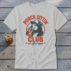White t-shirt with distressed graphic of bear in hat drinking from jar, "Porch Sittin' Club" text.