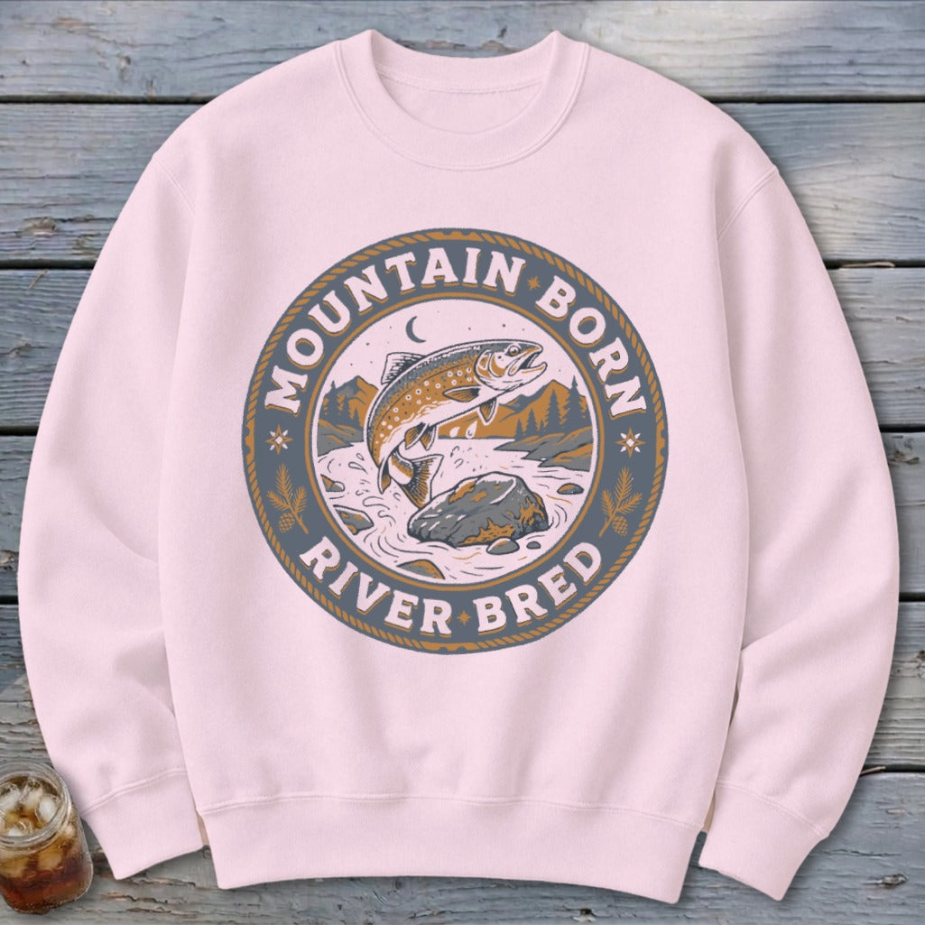 Pink sweatshirt with circular graphic of a jumping trout, text "Mountain Born River Bred."