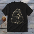 Black t-shirt with illustration of a bear carving wood with a knife.