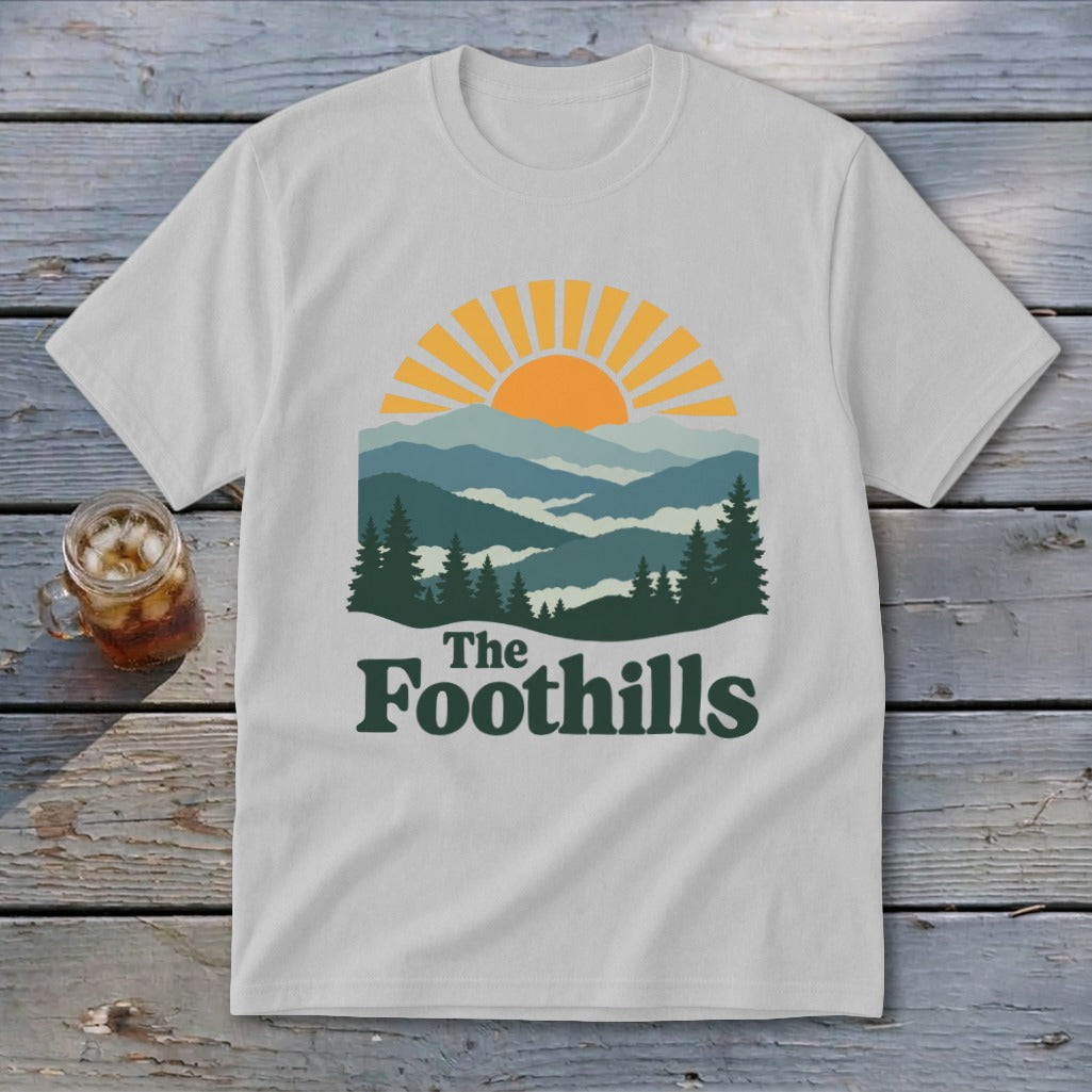White t-shirt with a vintage mountain sunrise graphic and "The Foothills" text.