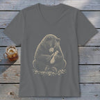 Bear carving a wooden object with a knife on a grey v-neck t-shirt.
