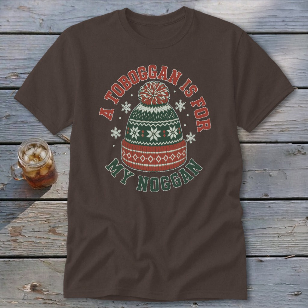 Brown t-shirt featuring a graphic of a winter beanie, snowflakes, and text reading A TOBOGGAN IS FOR MY NOGGAN.