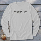 White long-sleeve shirt with "fixin' to" printed in black text.