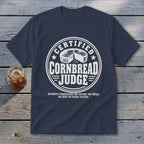 Navy blue t-shirt featuring a circular white graphic that reads CERTIFIED CORNBREAD JUDGE with a cornbread illustration.
