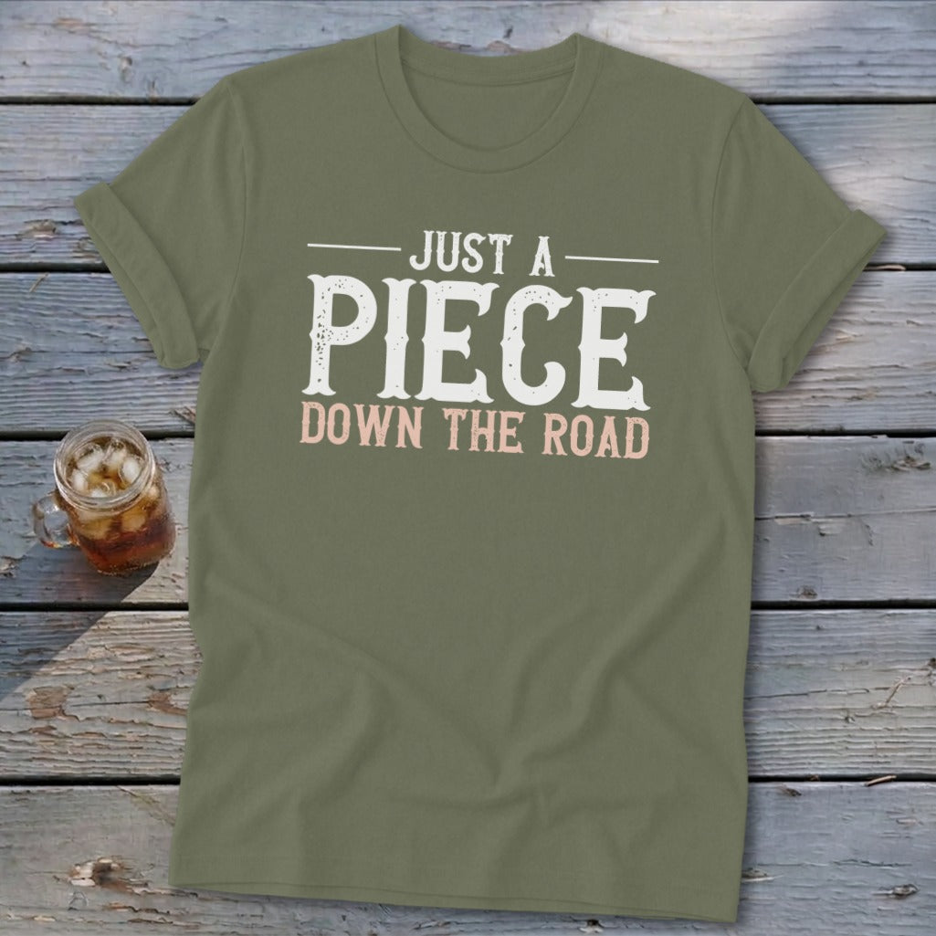 Olive green t-shirt with text "JUST A PIECE DOWN THE ROAD."