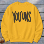 Yellow sweatshirt with dark brown text that reads "YOU'UNS".