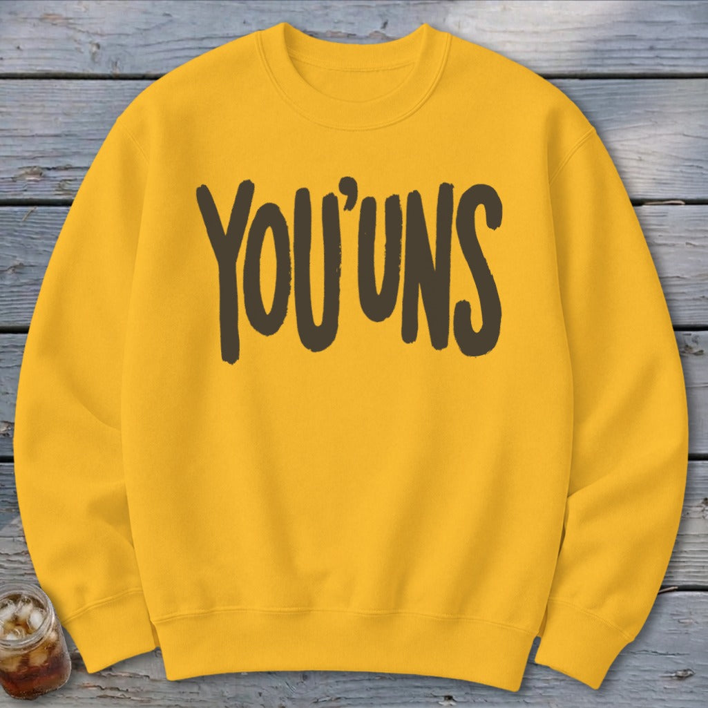 Yellow sweatshirt with dark brown text that reads "YOU'UNS".