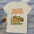 Cream t-shirt with "Dulcimer Dreams" text, dulcimer, mountains, and flowers graphic.