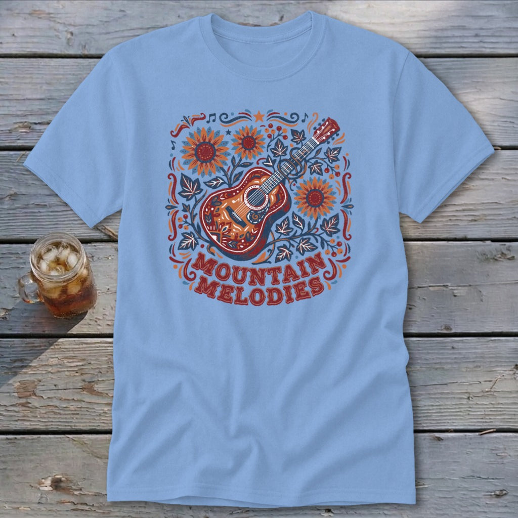 Light blue t-shirt featuring a folk art illustration of a guitar, sunflowers, and the text Mountain Melodies.