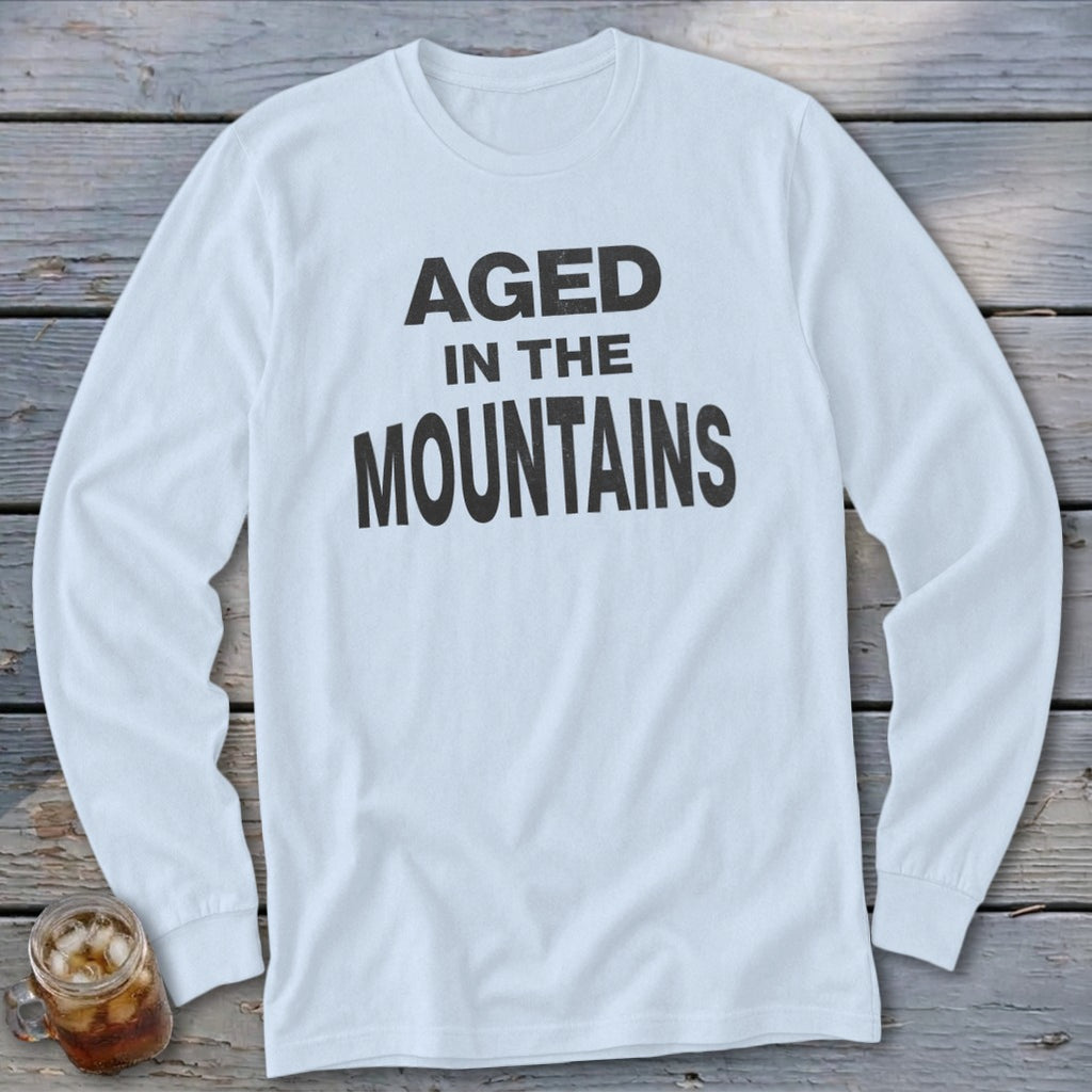 White long-sleeve t-shirt with black text reading "AGED IN THE MOUNTAINS".