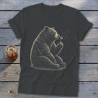 Graphic of a bear sitting and blowing on a dandelion on a dark t-shirt.