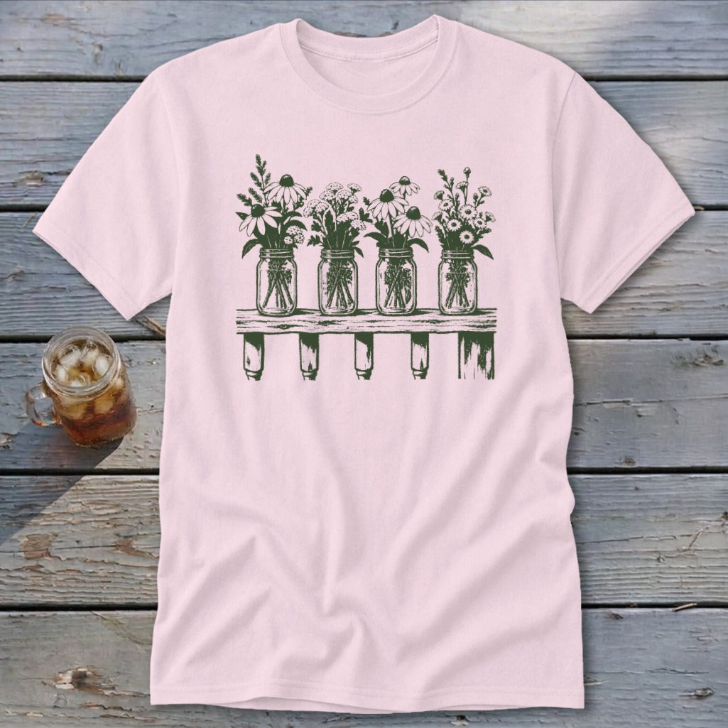 A pink crewneck t-shirt featuring a green graphic of four mason jars filled with wildflowers on a shelf.