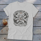 White t-shirt with "Stitched by Kin Every Square Tells a Story" graphic.