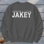 Dark grey crewneck sweatshirt with white text "LOOKING A LITTLE JAKEY".