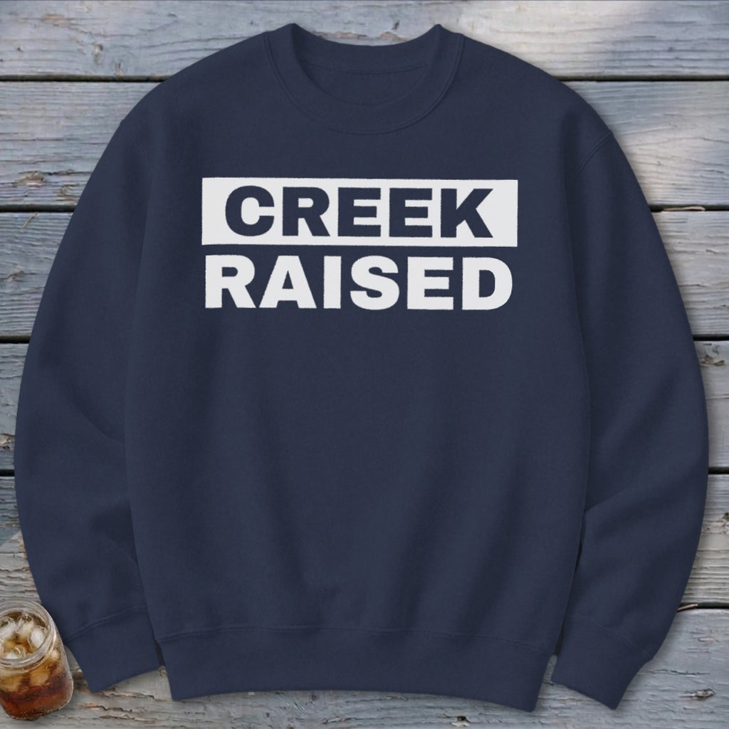 Navy sweatshirt with white text that reads "CREEK RAISED"