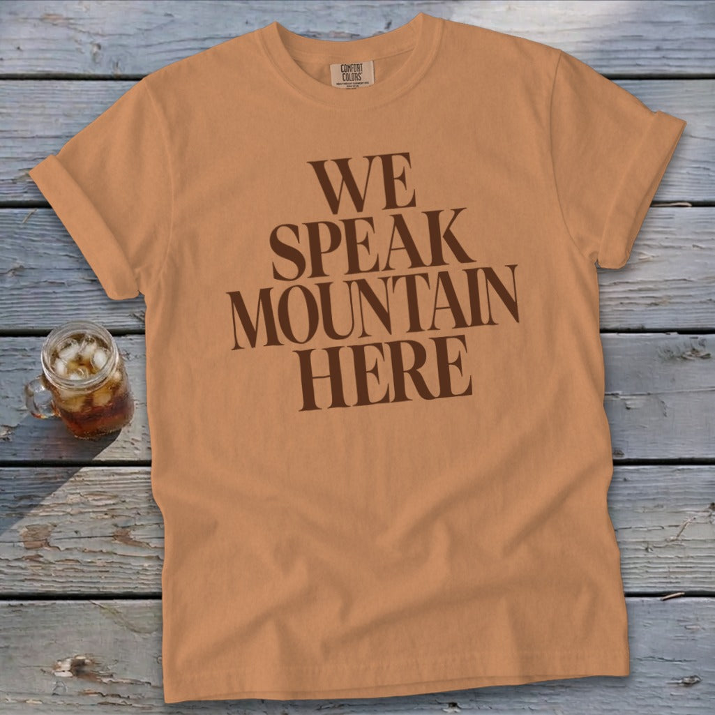 Orange t-shirt with brown text reading "WE SPEAK MOUNTAIN HERE."