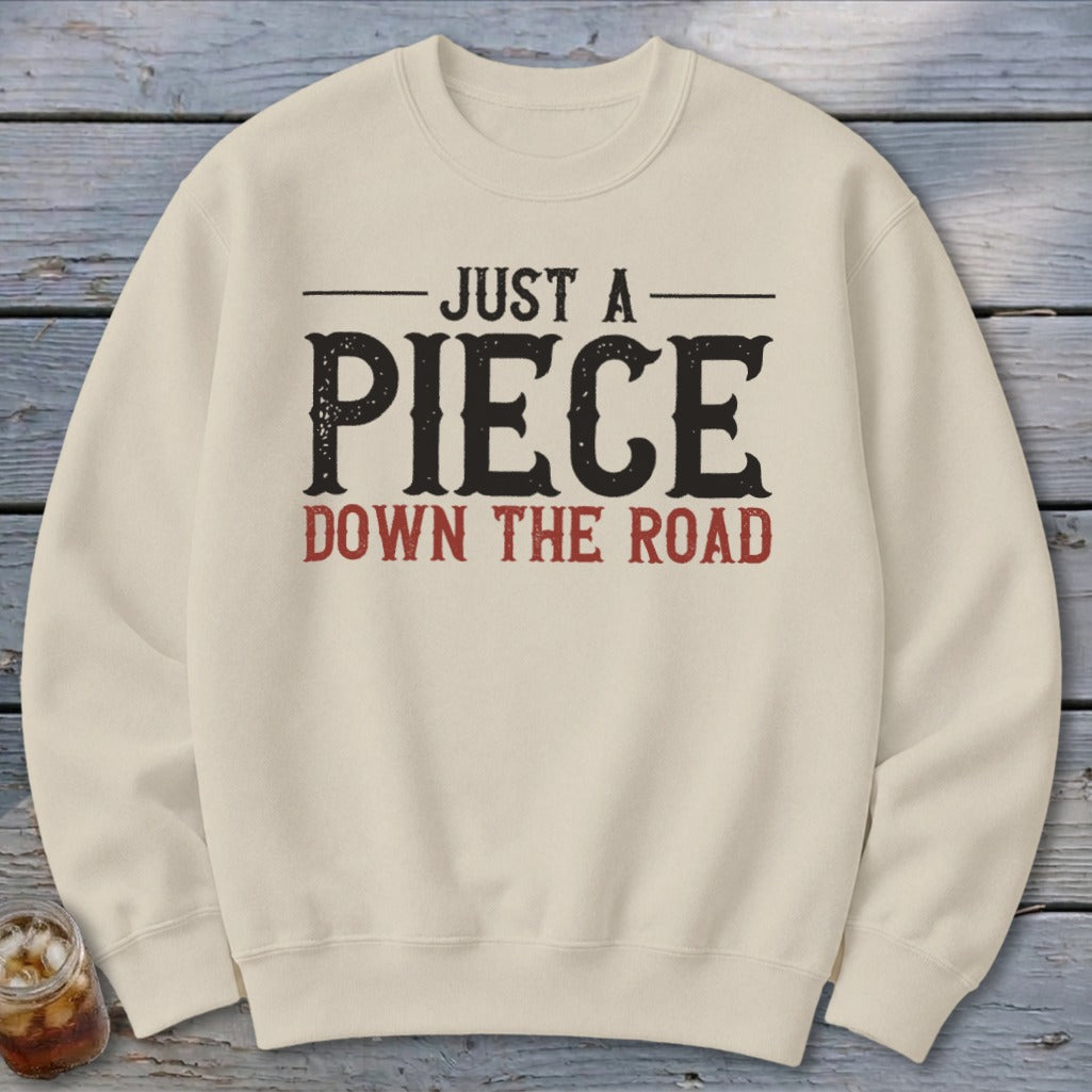 Cream sweatshirt with "Just a Piece Down the Road" text graphic.