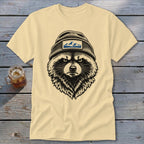 Light yellow t-shirt with a black and white illustration of a raccoon wearing a beanie with a mountain patch.