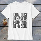 A white V-neck t-shirt with the text "Coal dust in my veins, mountains in my soul" printed in black.